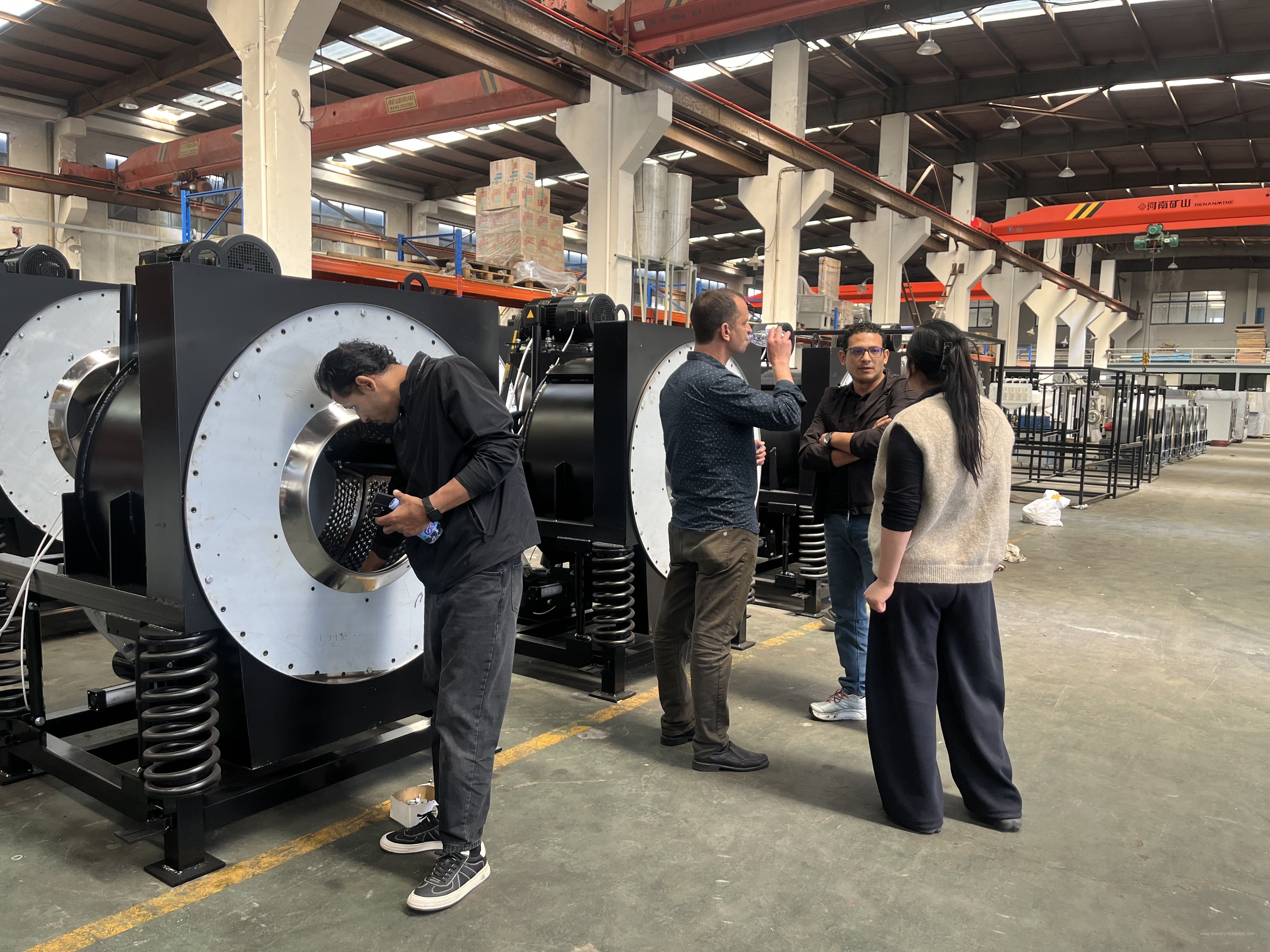 Visitors inspecting industrial washer construction in the factory