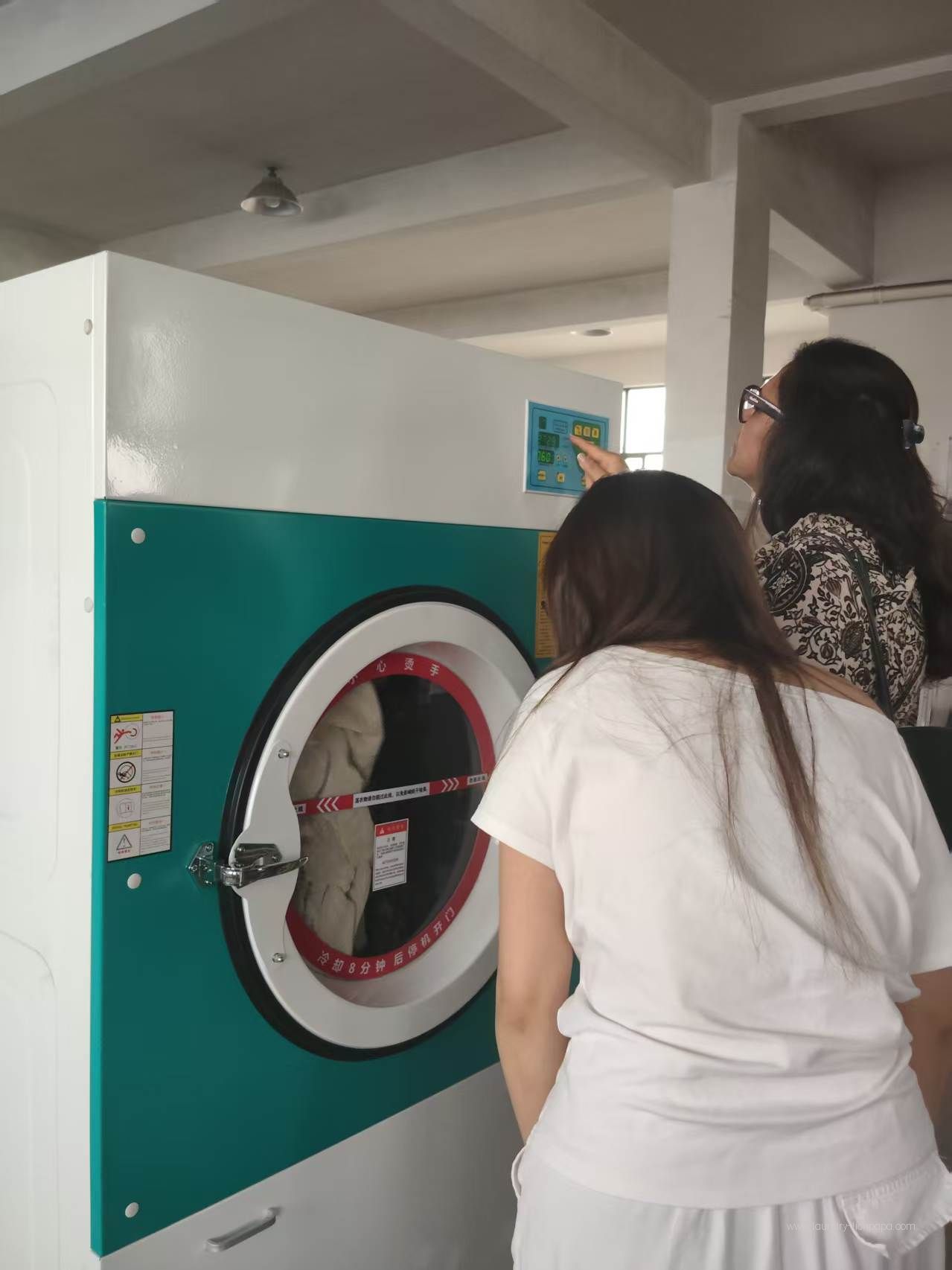 Visitors examining a laundry machine and its controls